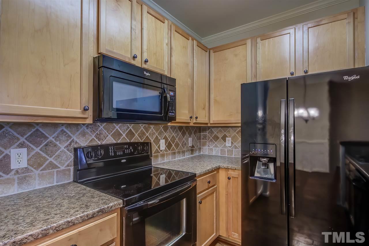 201 West Savannah Ridge Road, Unit 201 Holly Springs, NC 27540 - Photo 19 of 30 a kitchen with granite countertop a refrigerator stove and microwave