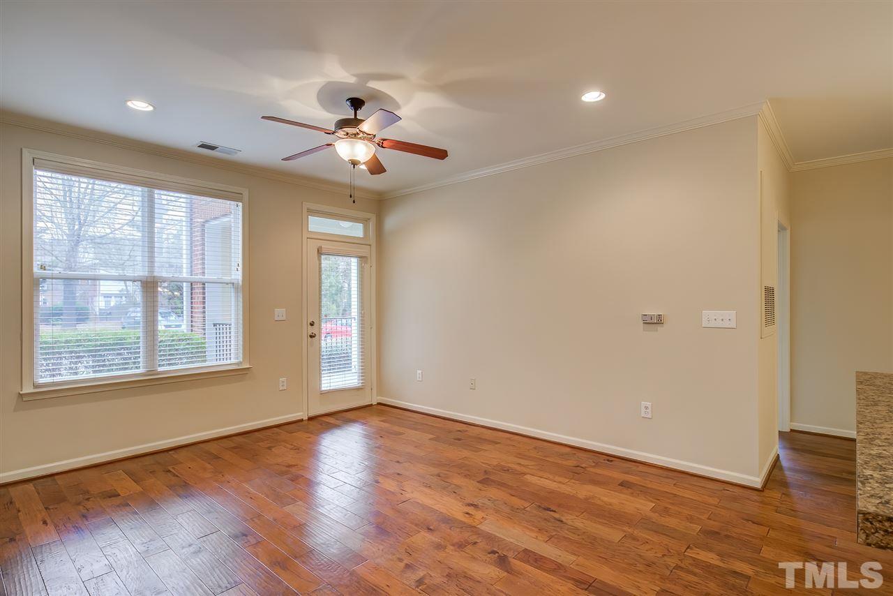 201 West Savannah Ridge Road, Unit 201 Holly Springs, NC 27540 - Photo 5 of 30 an empty room with wooden floor chandelier fan and windows