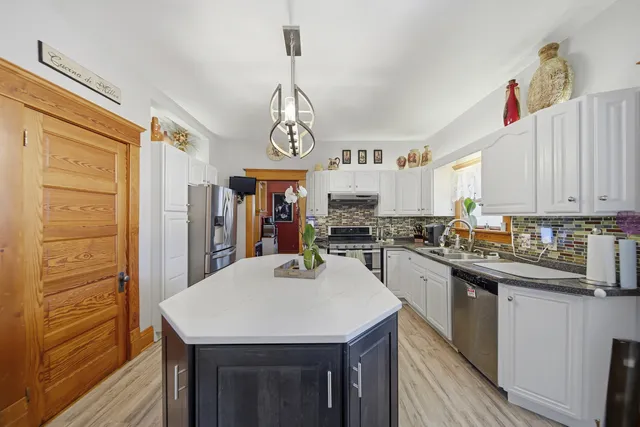 a kitchen with stainless steel appliances kitchen island granite countertop a table chairs in it and wooden floors