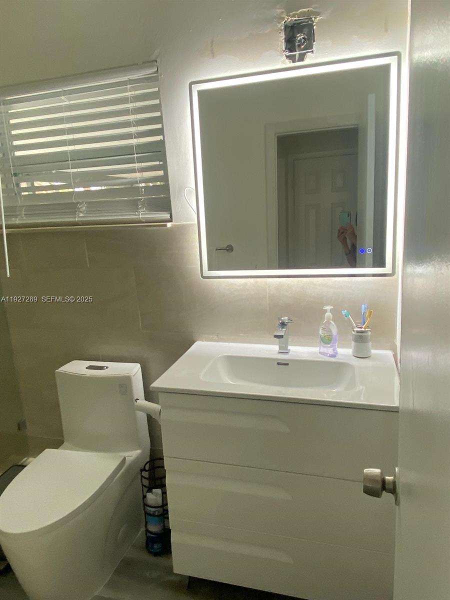 1641 Northwest 9th Street Boca Raton, FL 33486 - Photo 8 of 11 a bathroom with a toilet sink and mirror