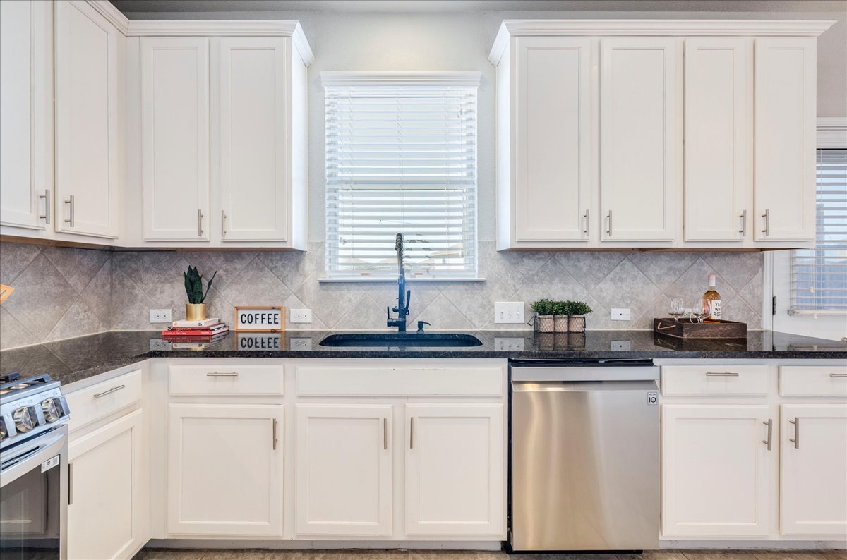 312 Triumph Road Buda, TX 78610 - Photo 17 of 36 a kitchen with granite countertop white cabinets and white appliances