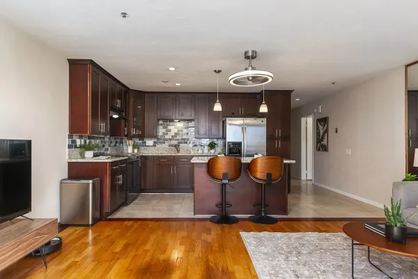 a kitchen with stainless steel appliances granite countertop a refrigerator a sink a stove a dining table and chairs