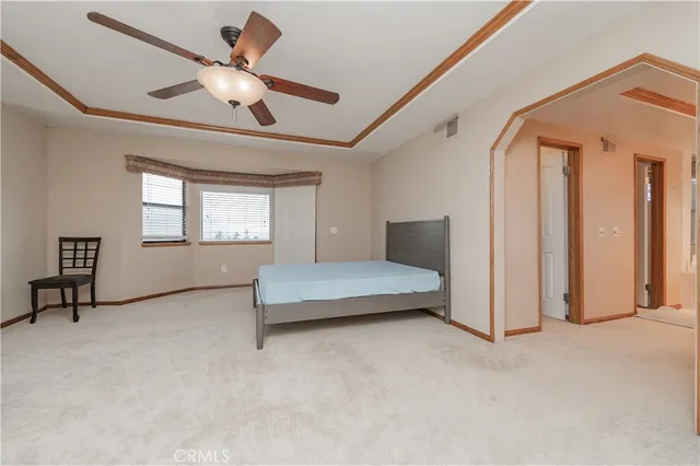 an empty room with a chandelier fan and closet area