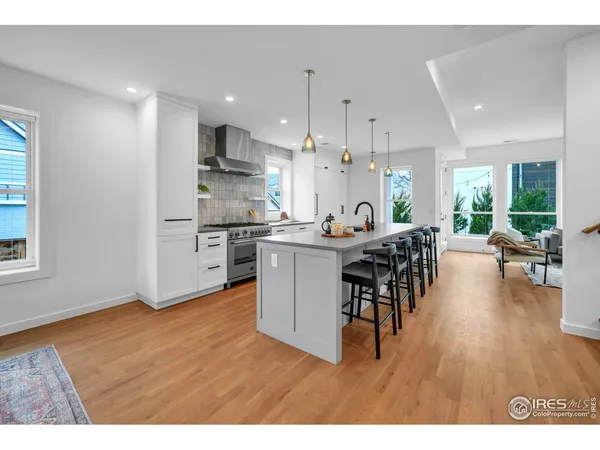 a open kitchen with stainless steel appliances granite countertop a table chairs and a refrigerator