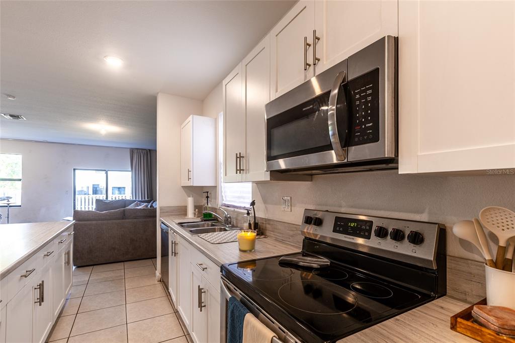 25190 Southwest 107th Avenue Homestead, FL 33032 - Photo 47 of 57 a kitchen with stainless steel appliances a sink a stove cabinets and a microwave