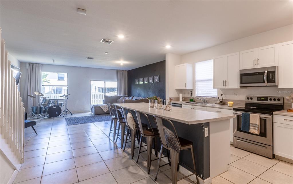 25190 Southwest 107th Avenue Homestead, FL 33032 - Photo 50 of 57 a open kitchen with stainless steel appliances granite countertop a stove top oven a sink dishwasher a dining table and chairs with wooden floor