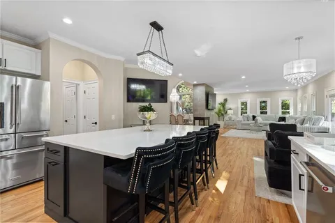 a open kitchen with stainless steel appliances granite countertop a stove a refrigerator a couch and a dining table with wooden floor