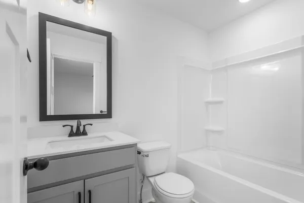 a bathroom with a bathtub shower sink vanity mirror and toilet