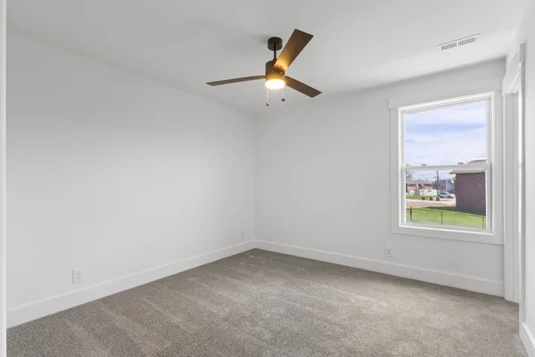an empty room with a window and a ceiling fan