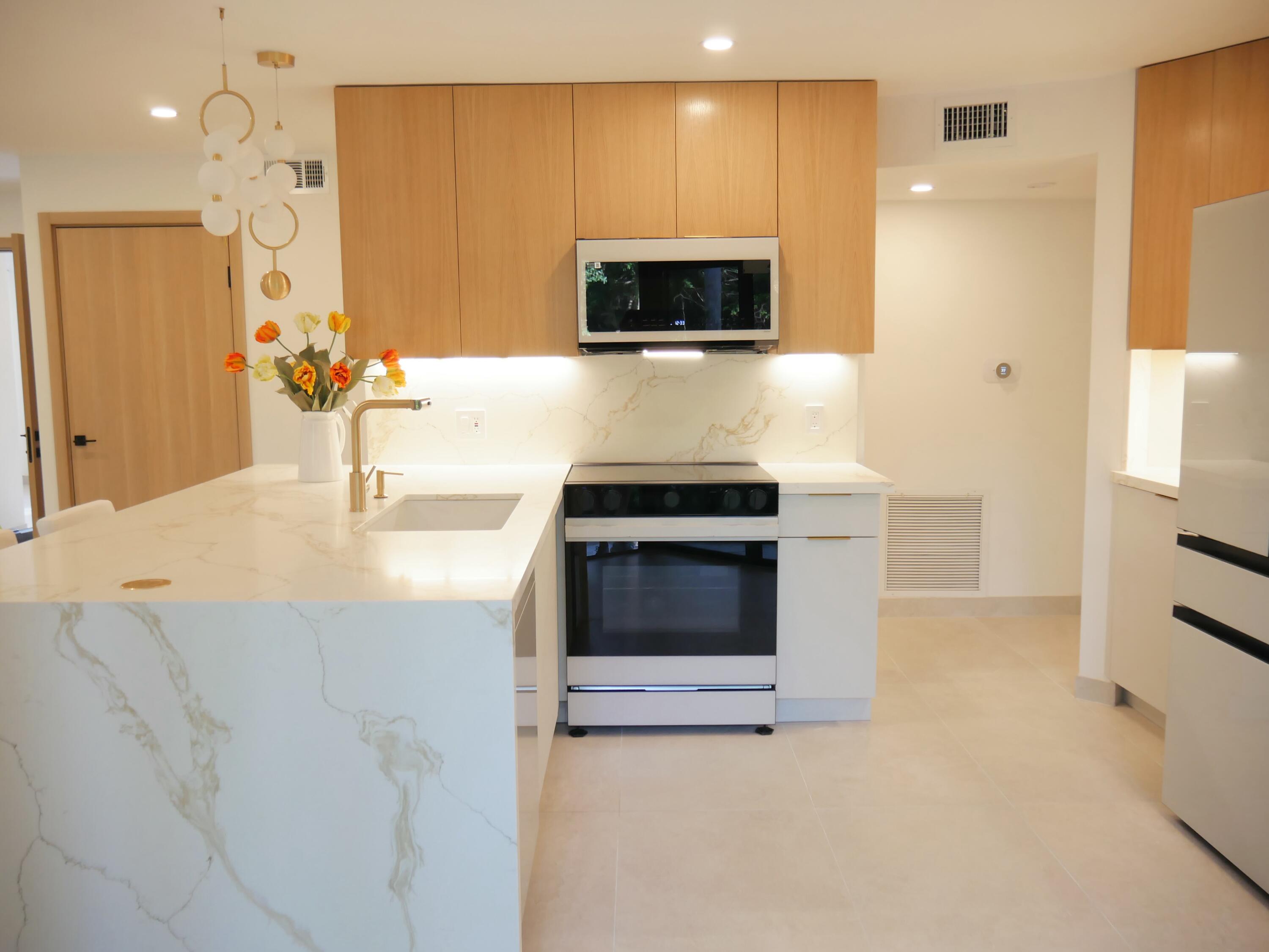 5630 Coach House Circle, Unit D Boca Raton, FL 33486 - Photo 8 of 26 a kitchen with stainless steel appliances a stove a microwave and white cabinets