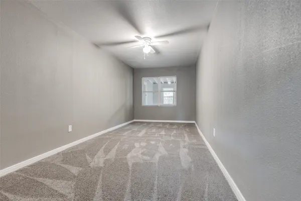 a view of an empty room with window and chandelier fan