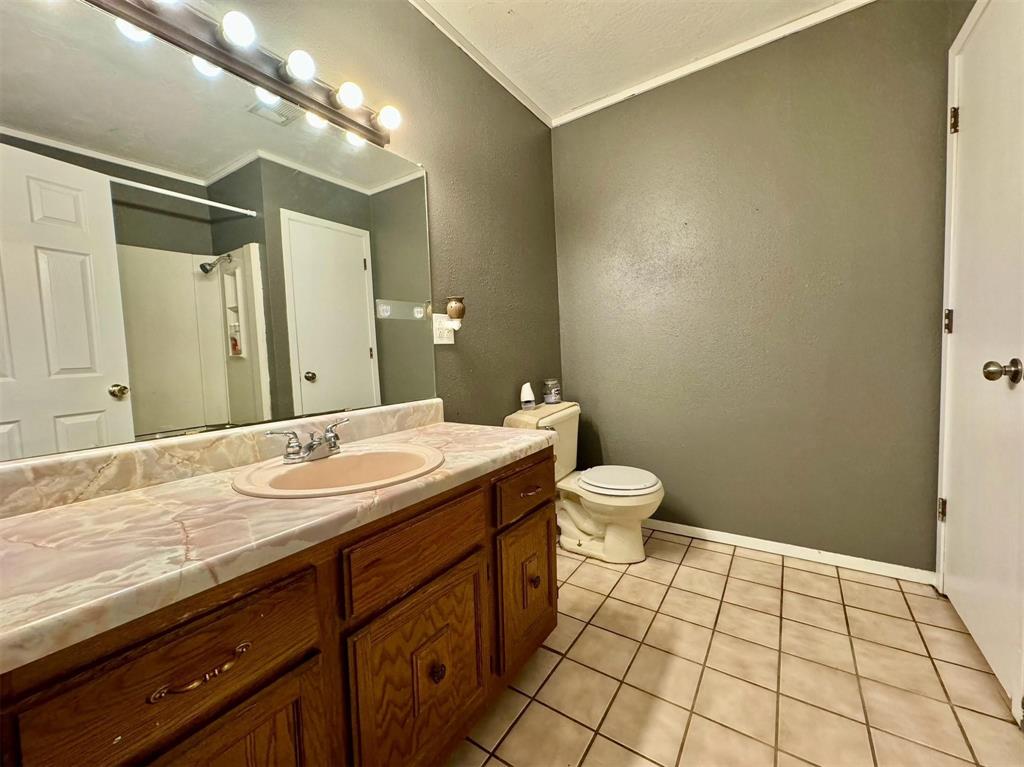 1319 West Morgan Street Denison, TX 75020 - Photo 12 of 17 a bathroom with a granite countertop sink a toilet and a mirror