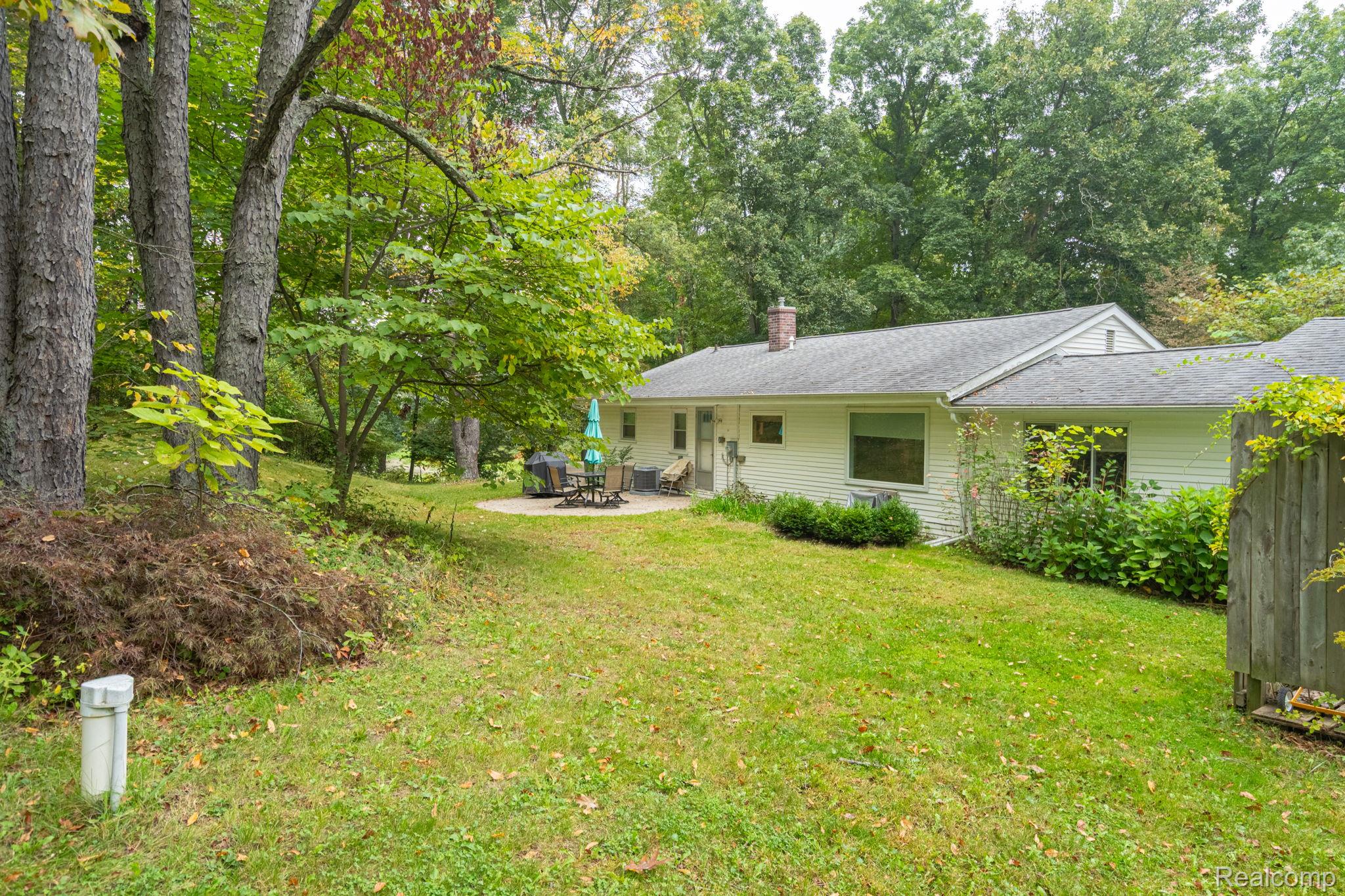 1775 Porter Road White Lake, MI 48383 - Photo 12 of 33 Expansive backyard featuring a manicured lawn, established trees, and a circular patio
