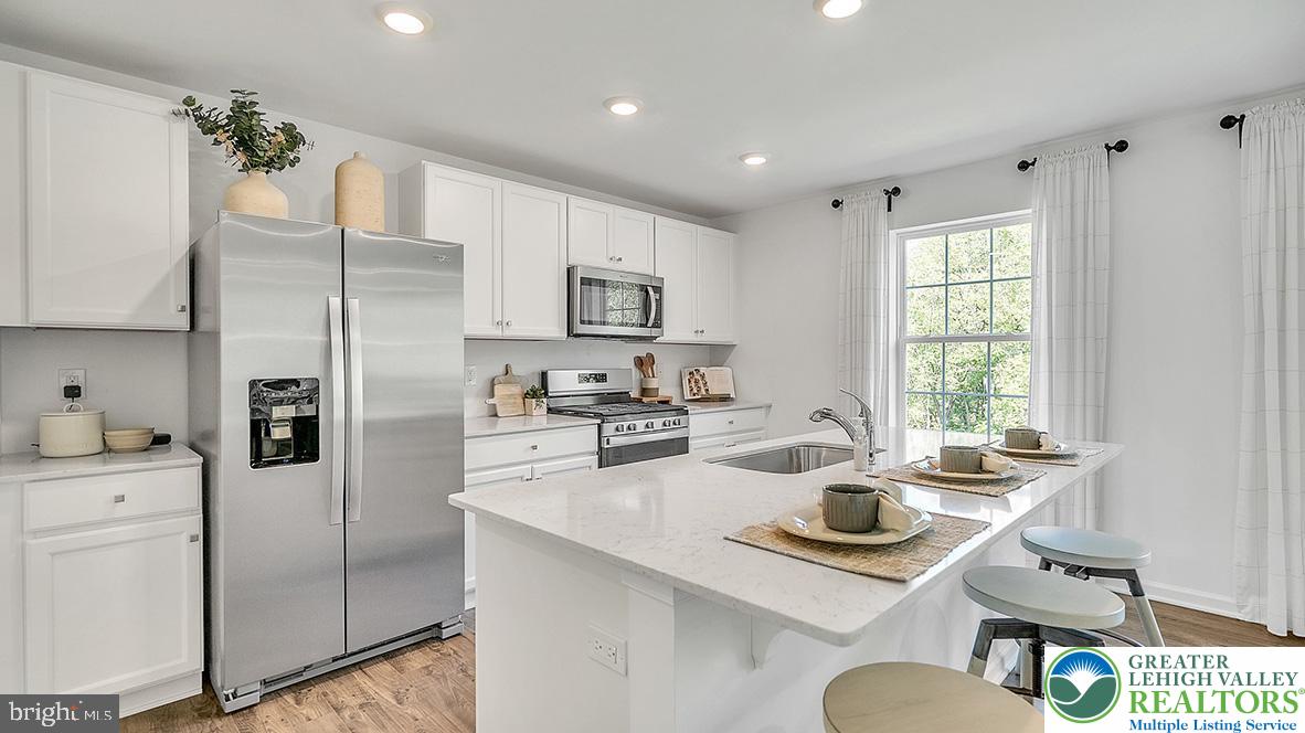 115 Winding Road Easton, PA 18040 - Photo 7 of 24 This modern kitchen features a spacious island with seating and sleek appliances, perfect for culinary endeavors.