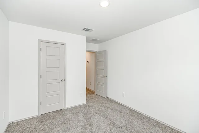 an empty room with closet and a ceiling fan