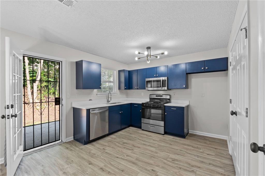 2921 Ward Lake Way Ellenwood, GA 30294 - Photo 10 of 25 a kitchen with stainless steel appliances granite countertop a stove top oven a sink dishwasher a refrigerator and a dining table with wooden floor