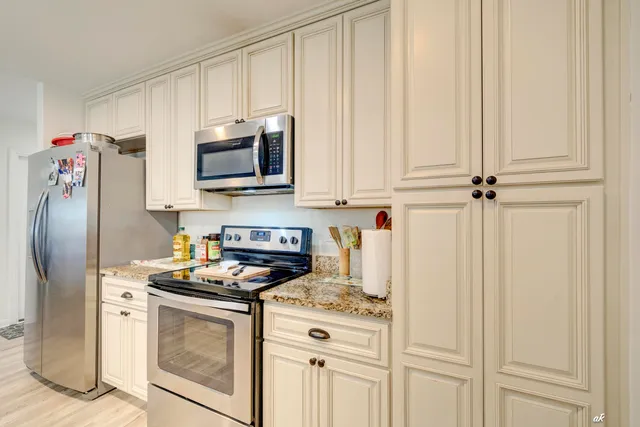 a kitchen with stainless steel appliances granite countertop a stove a refrigerator and a microwave