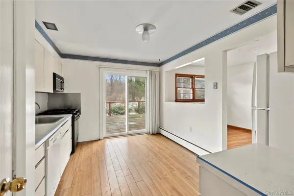 a kitchen with granite countertop a stove top oven a sink dishwasher a refrigerator and a fireplace with wooden floor