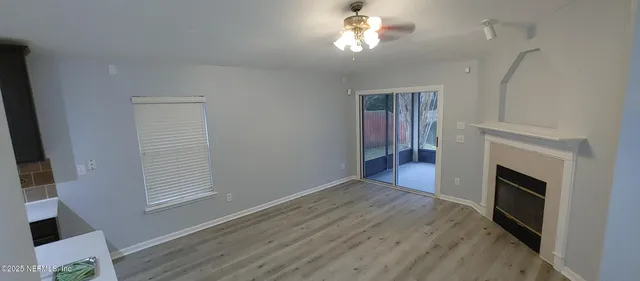 an empty room with windows fireplace and wooden floor