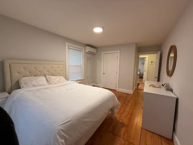 a bedroom with a bed a mirror on dresser and a dresser