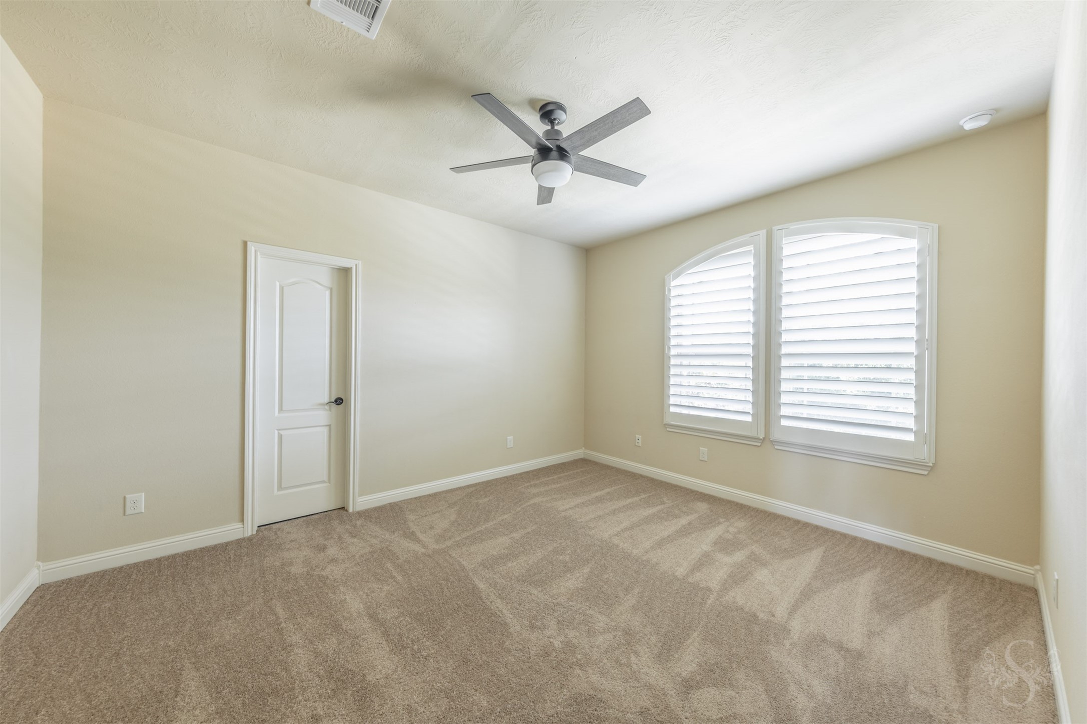5803 Mustang Ridge Lane Fulshear, TX 77441 - Photo 33 of 48 Secondary bedroom offers generous space, plush carpeting and elegant arched windows with plantation shutters that add character and privacy. Soft neutral finishes create a versatile space ideal for guests, family or a private retreat.