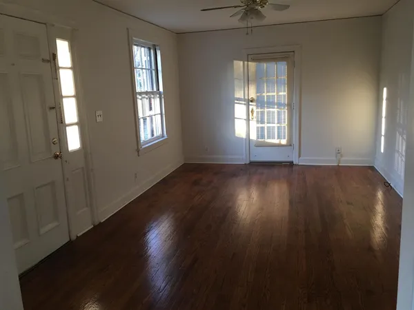 an empty room with wooden floor and windows