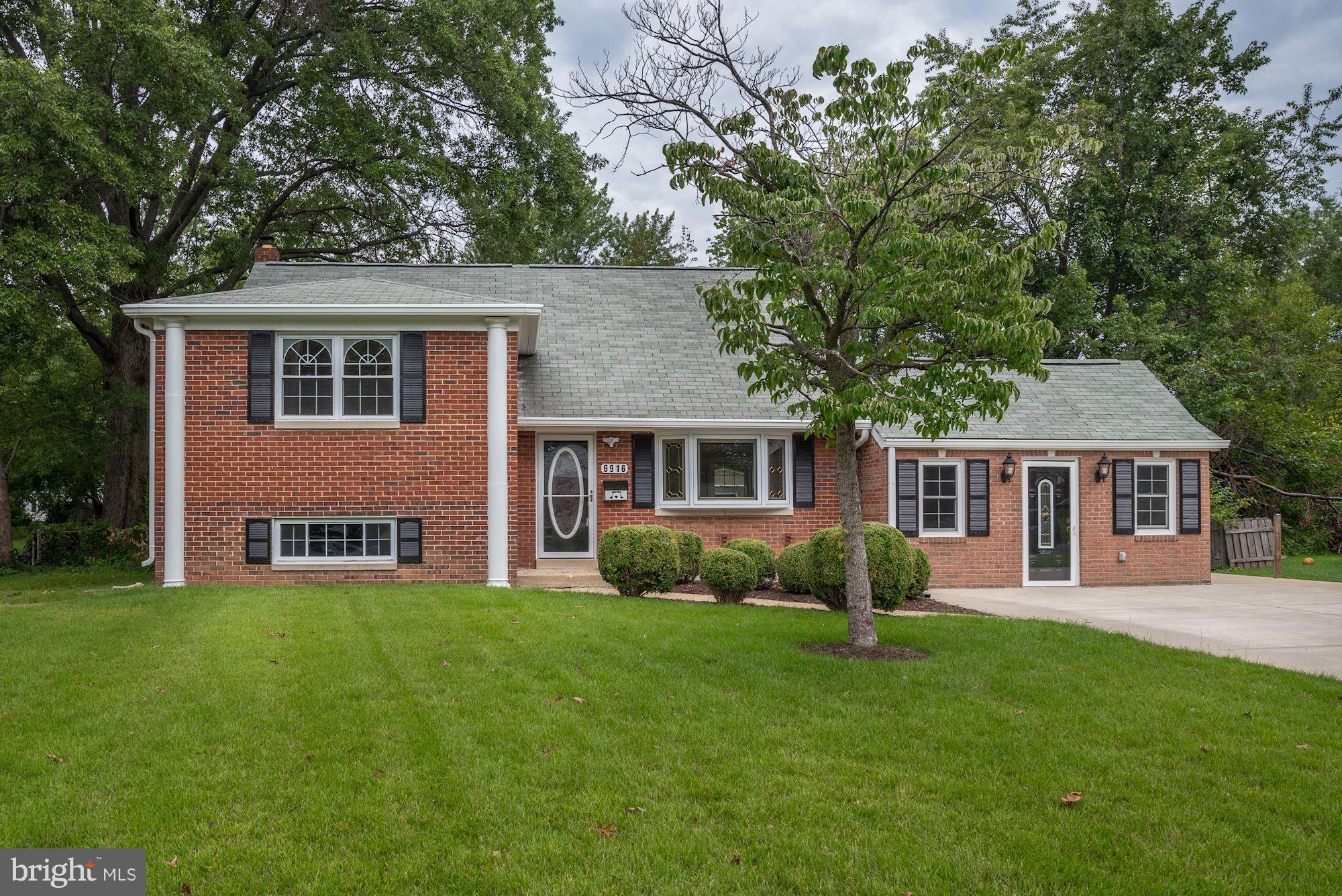 a front view of a house with a garden and trees