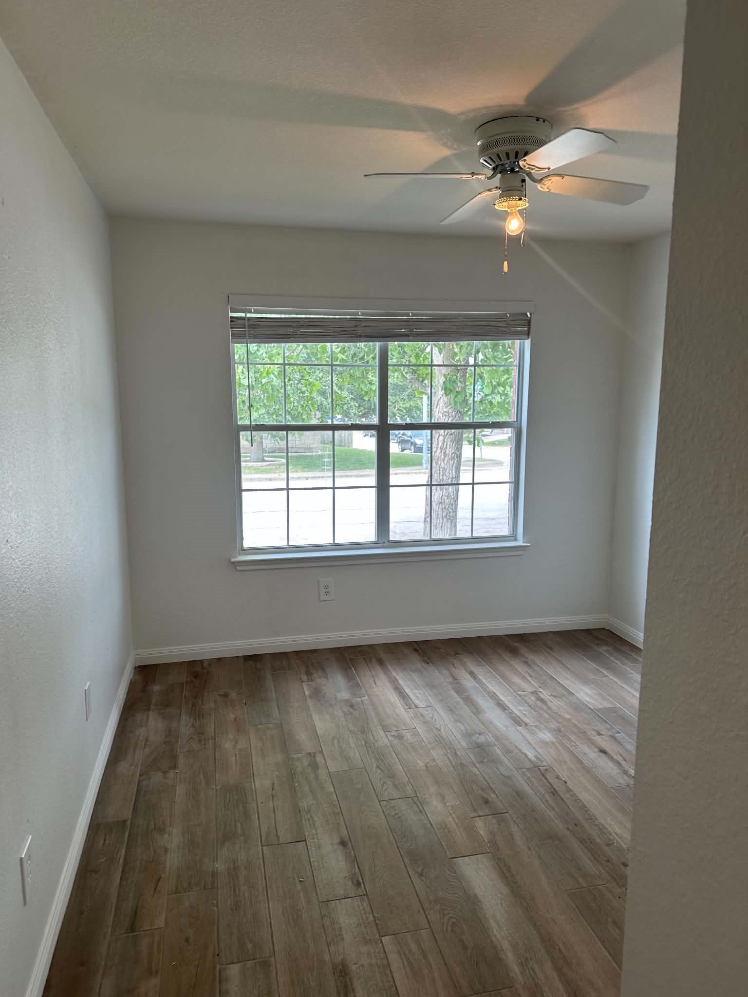 18312 Crestwind Lane Elgin, TX 78621 - Photo 7 of 15 Well-lit room with wood flooring and a view of the surrounding greenery.