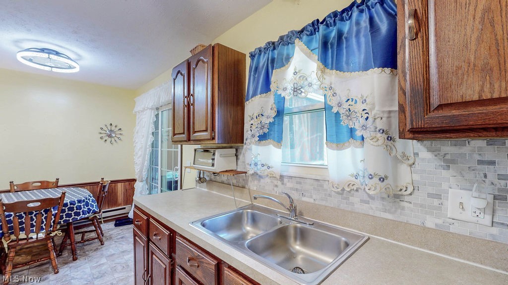 38667 Chestnut Ridge Road Elyria, OH 44035 - Photo 11 of 35 Kitchen featuring a double stainless steel sink, light-toned countertop, and mosaic tile backsplash