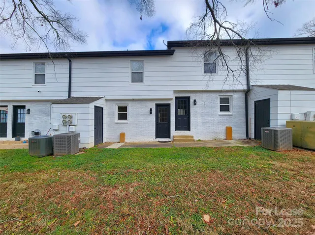 a view of a house with a yard and a large tree