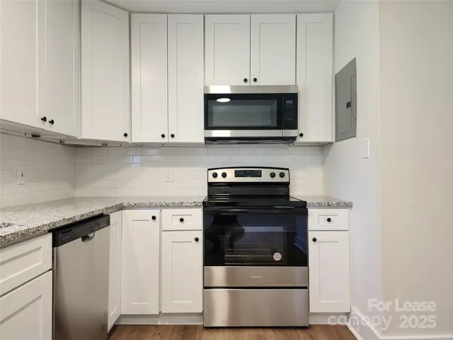 a kitchen with stainless steel appliances granite countertop a stove a microwave and a white cabinets