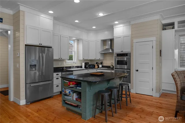 a kitchen with kitchen island stainless steel appliances a sink and refrigerator