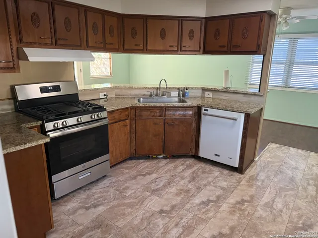 an empty room with wooden floor chandelier fan and windows