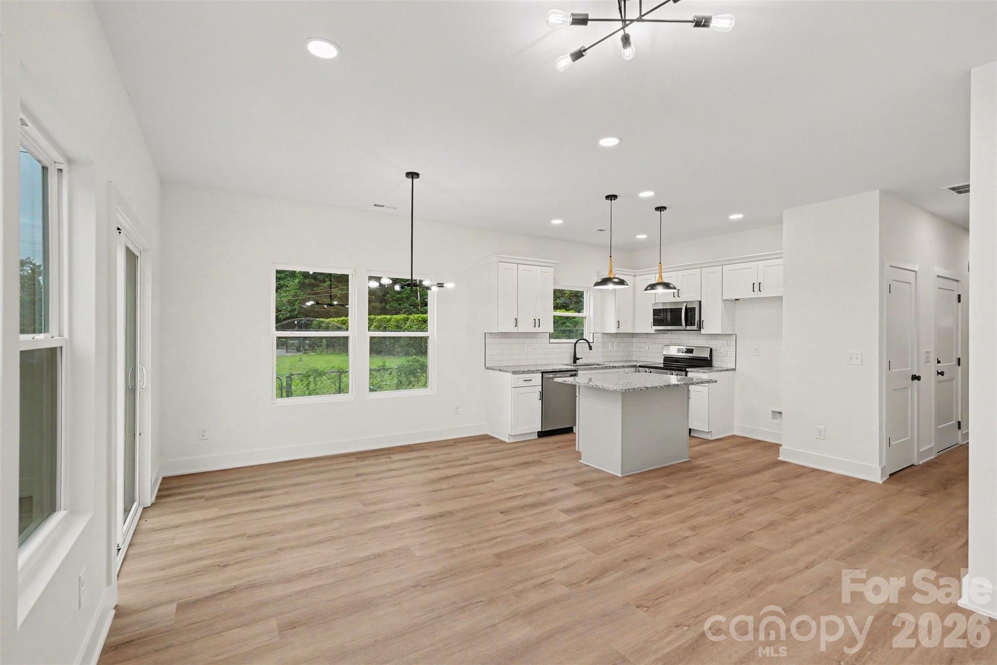 7521 Lawyers Road Charlotte, NC 28227 - Photo 13 of 35 a large kitchen with kitchen island a stove a refrigerator a sink and a fireplace with wooden floor