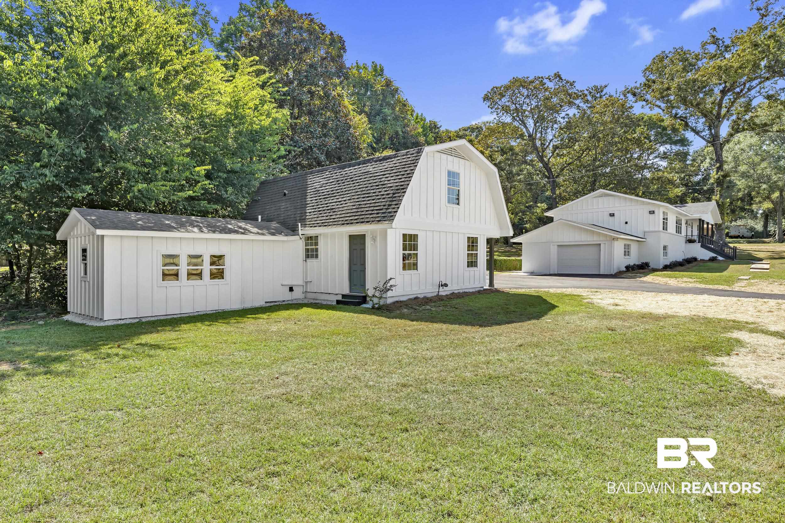 8351 Theodore Dawes Road Theodore, AL 36582 - Photo 4 of 46 View of front of property featuring board and batten siding, driveway, a gambrel roof, a front lawn, and a garage