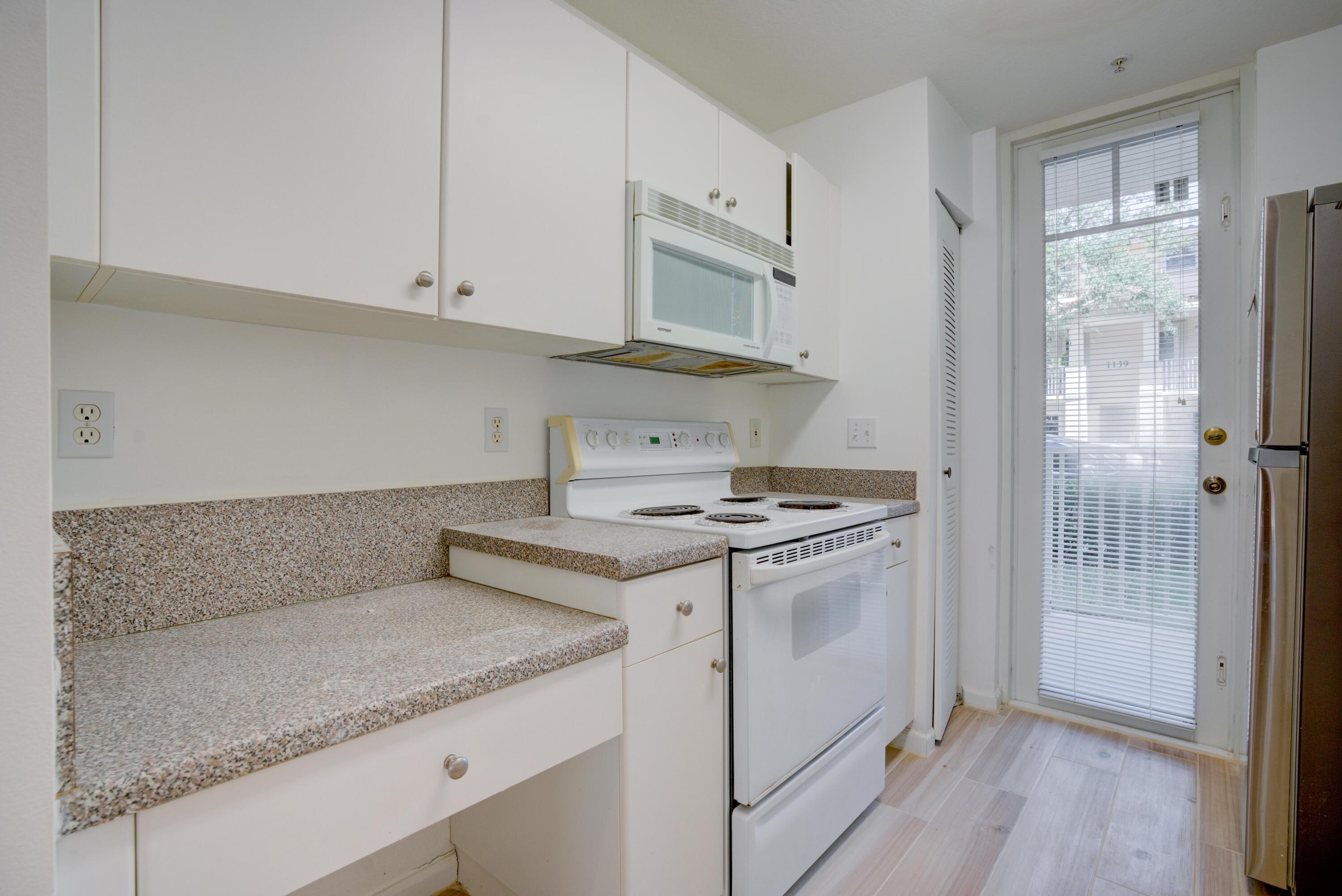 1136 Town Center Drive, Unit 11 Jupiter, FL 33458 - Photo 17 of 24 a kitchen with granite countertop a stove and a white cabinets