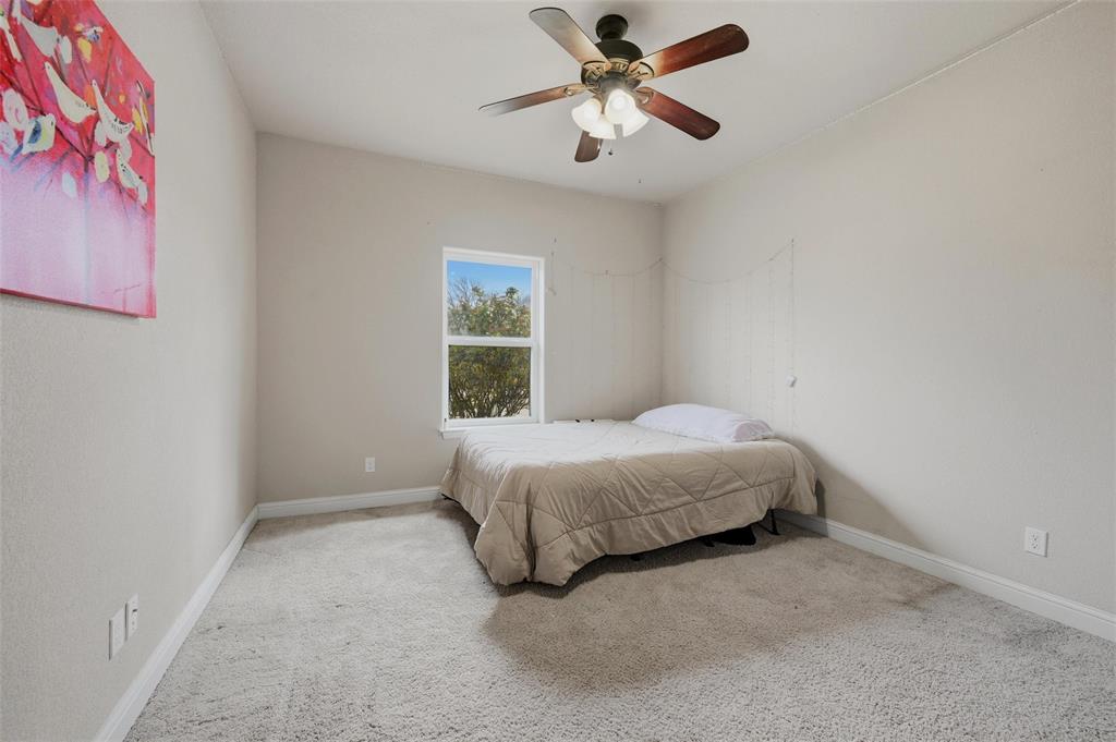 1959 Marlow Road Bells, TX 75414 - Photo 24 of 32 a spacious bedroom with a bed and a chandelier