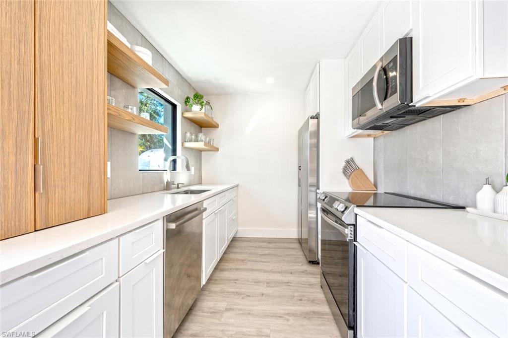 4608 Normandy Drive Naples, FL 34112 - Photo 12 of 49 a kitchen with a sink and wooden cabinets