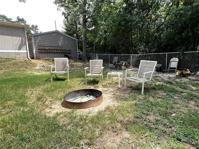 a view of a wooden house with a small yard and large trees