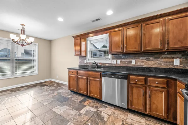 a kitchen with stainless steel appliances granite countertop a stove a sink and a microwave