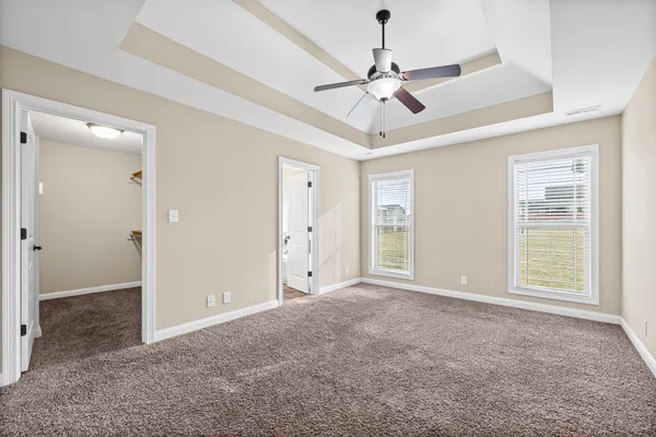 an empty room with chandelier fan and windows