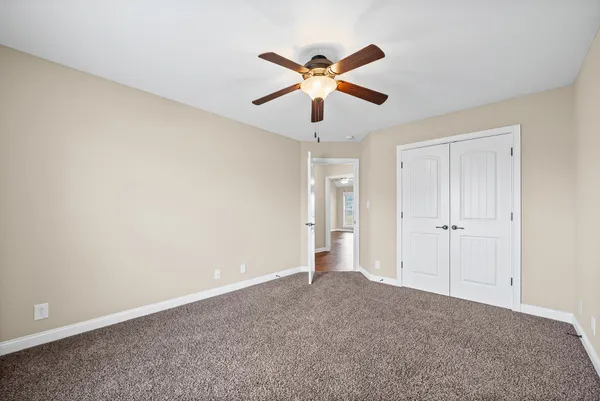 a view of an empty room and chandelier fan