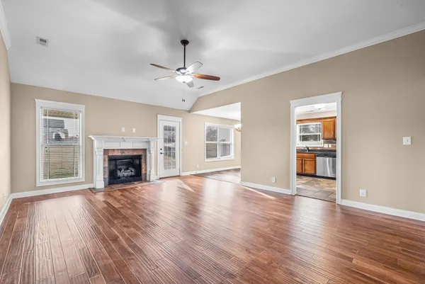 a view of an empty room with wooden floor fireplace and a window