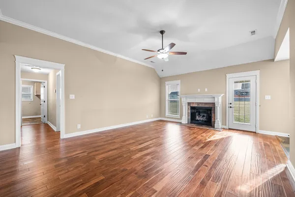 an empty room with wooden floor fireplace and windows