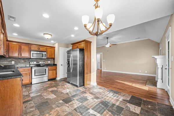 a large kitchen with stainless steel appliances kitchen island granite countertop a refrigerator and a stove top oven