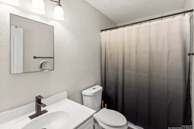 a bathroom with a sink a toilet and shower curtain
