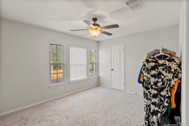 an empty room with windows and chandelier fan