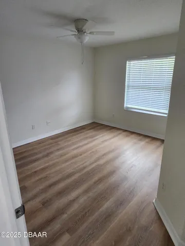 an empty room with wooden floor cabinet and windows