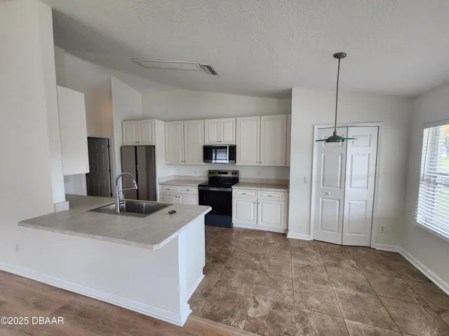 a kitchen with kitchen island granite countertop a refrigerator a sink a stove a microwave and wooden cabinets