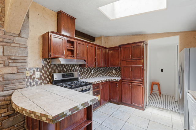 2875 North Hill Field Road, Unit 111 Layton, UT 84041 - Photo 7 of 30 Kitchen featuring open shelves, a skylight, stainless steel appliances, tasteful backsplash, and light tile patterned floors